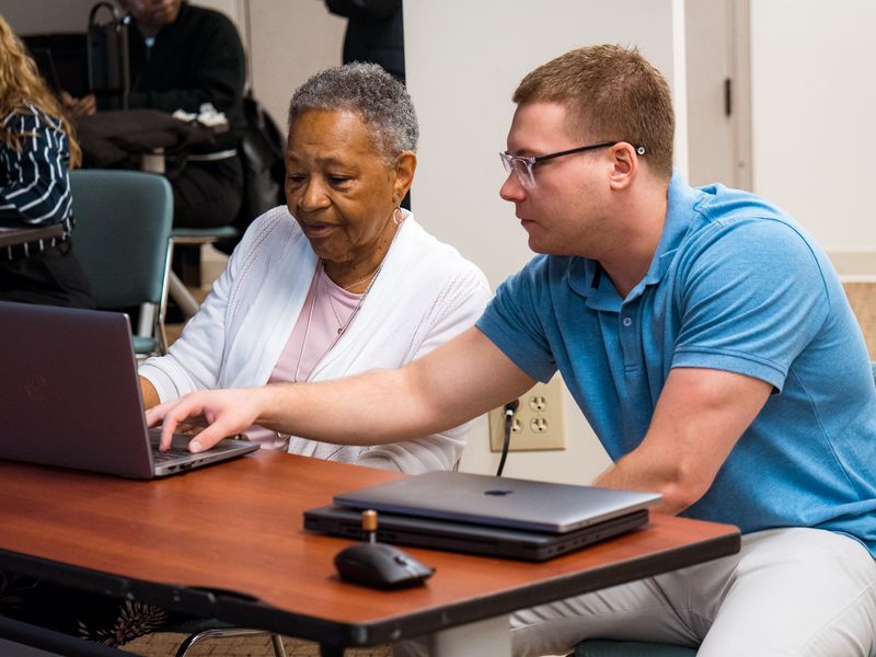 A teacher helping a participant with her laptop