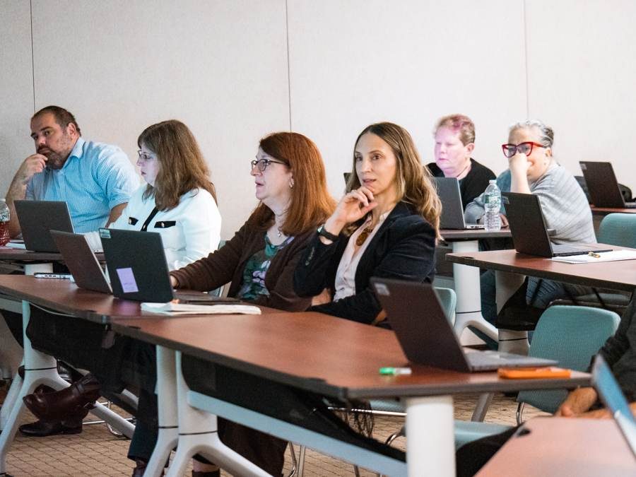 Participants at desks with laptops open during a seminar